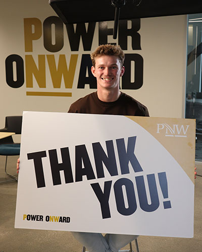 Harry Hooper sits on a stool and holds a "Thank You" sign