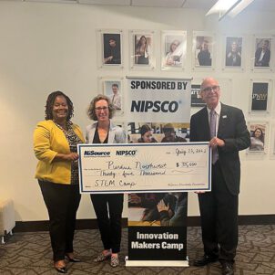 Three people stand with a large check. Left to right: Alexius Barber, Rachel Clapp-Smith, and PNW Chancellor Thomas L. Keon.