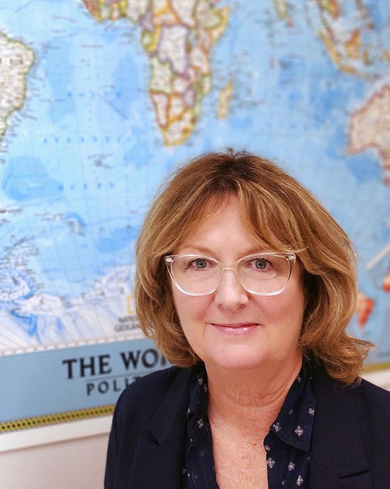 Kathy Tobin in front of a map of the world.