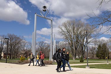 PNW students walk in front of the Bell Tower on campus.