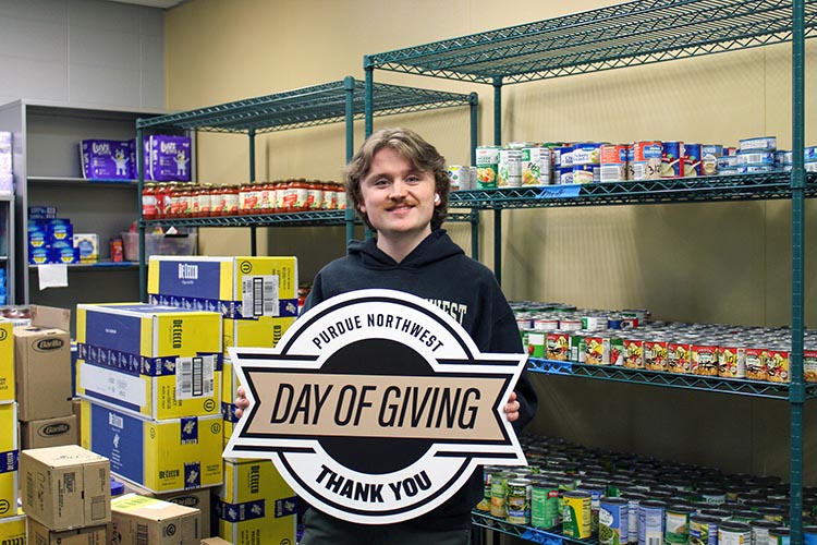 A student in the PNW Food Pantry holds a Purdue Northwest Day of Giving "Thank You" sign.