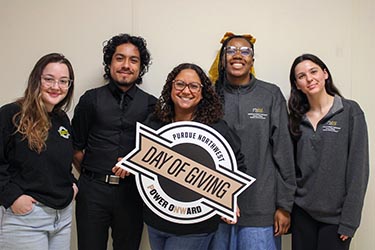 PNW students hold a sign that says Purdue Northwest Day of Giving Power Onward