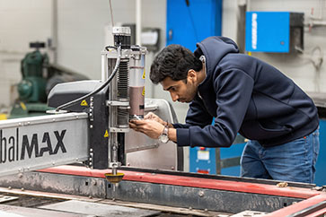 A technology student adjusts industrial machinery.