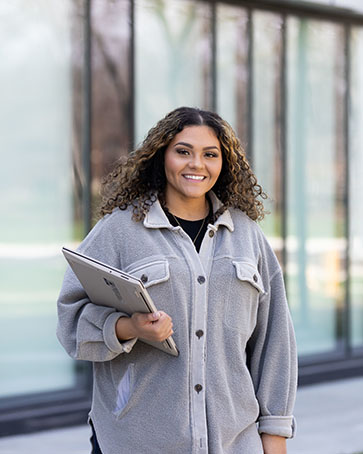 A PNW student stands in front of a building