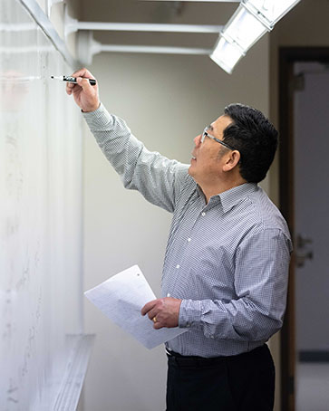 A professor writes on a dry erase board
