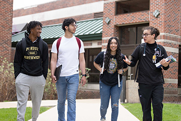 Four students walking out of a building while talking.