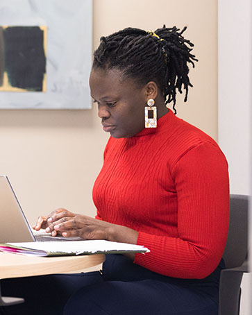 A PNW graduate student in a red shirt sits at a laptop