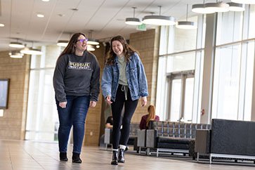 Two students walk side by side through a hallway