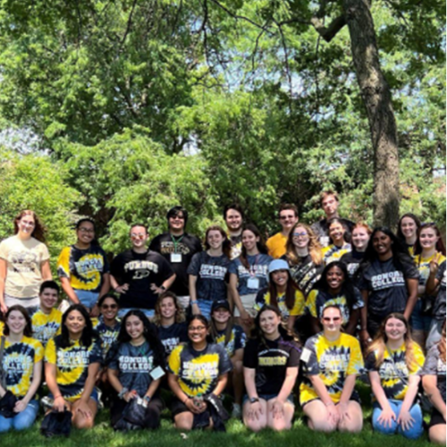Students in "honors college" t-shirts pose together in a wooded area.