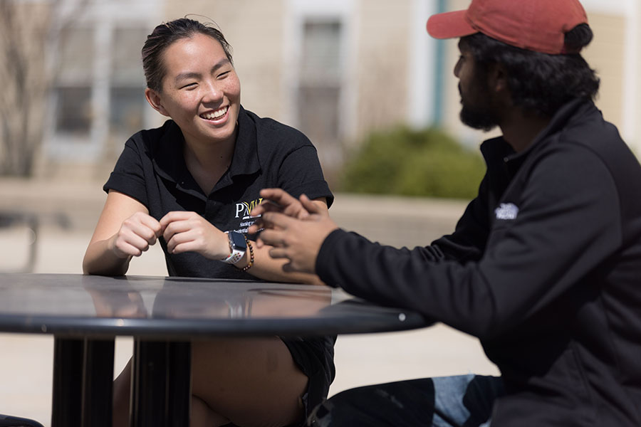 students sit outside at a table.