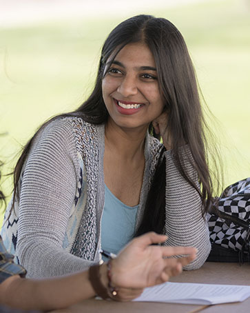 Student sits at a picnic table at the dorms