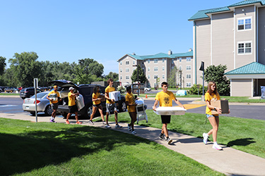 Students carrying boxes and dorm products outside