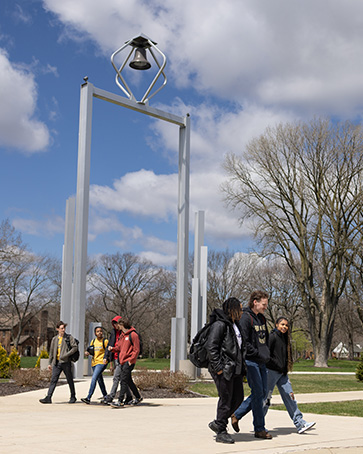 6 students walking past the bell tower