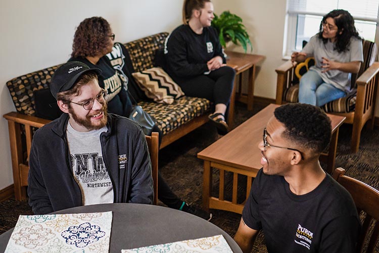 5 PNW students in a dorm room while talking to one another