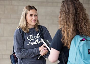 Two students stand together outside.