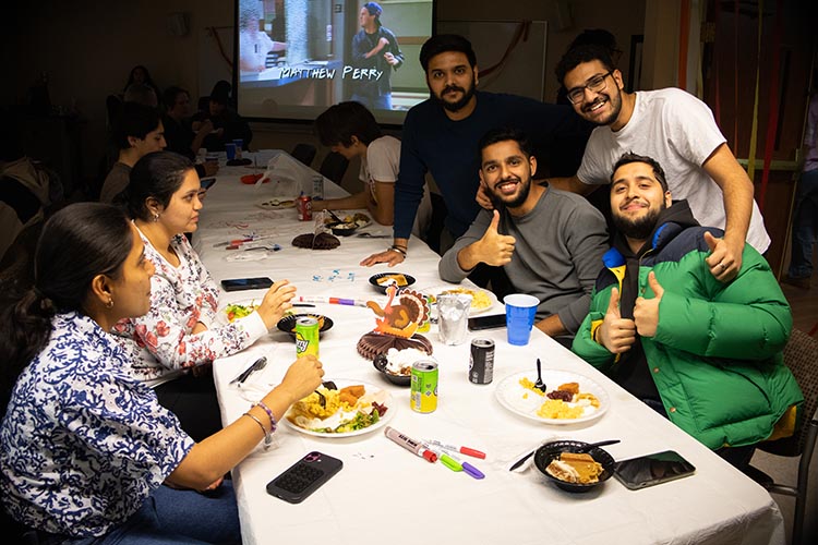 A group of PNW students sitting together at a table at Friendsgiving.