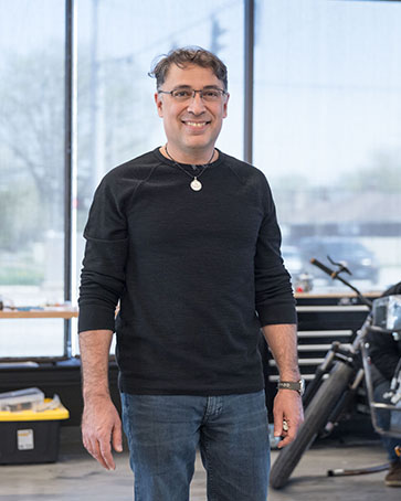 A professor stands in a mechanic shop