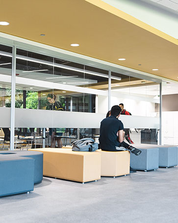 A person sits on a couch while others walk by
