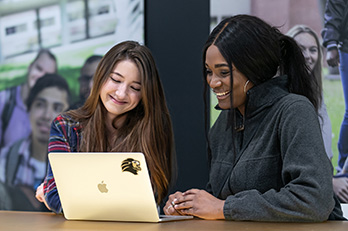 Two PNW students around a laptop.