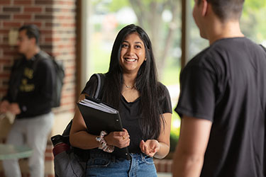 A student smiles while holding a folder.