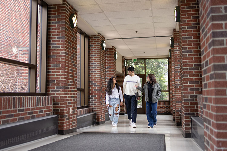 Three students walk on campus