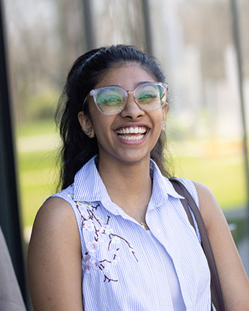 A PNW international student in glasses laughs outdoors