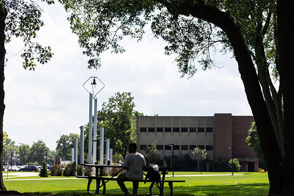 A student sits at a picnic table by the bell tower on PNW's Hammond Campus.