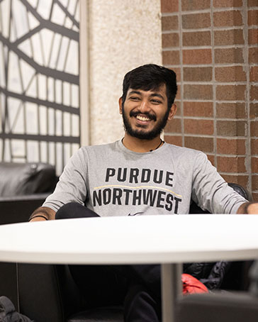A student sits at a table indoors and laughs