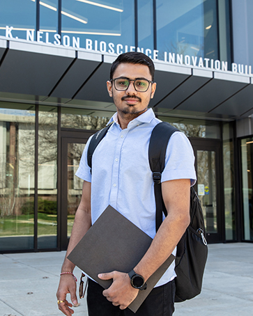 A student stands in front of the Nils building.