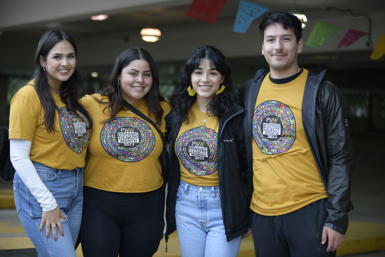 Four students in matching PNW Hispanic Heritage Month shirts pose together