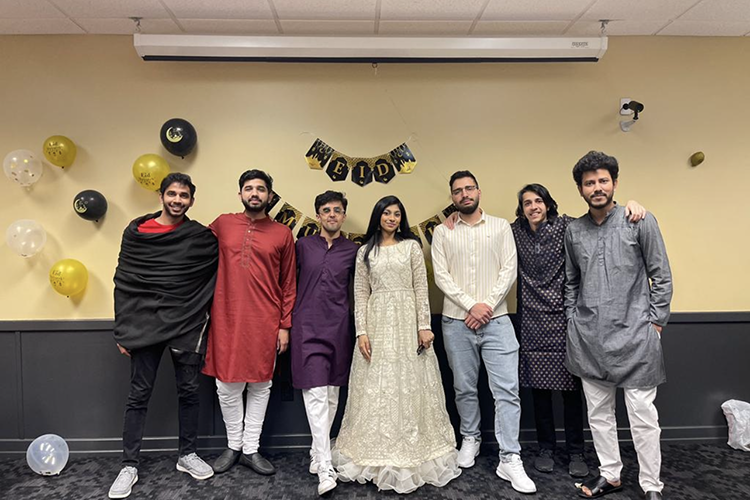 Seven students pose together in traditional Islamic outfits during Eid celebrations