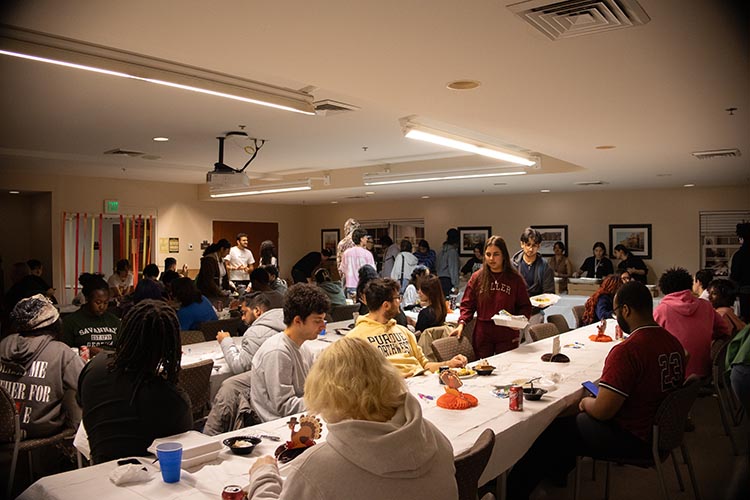 PNW students all talking to one another in a dorm hall at Friendsgiving.