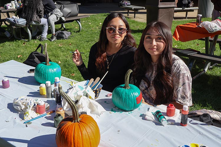 Two PNW students painting pumpkins during Pumpkin Week.