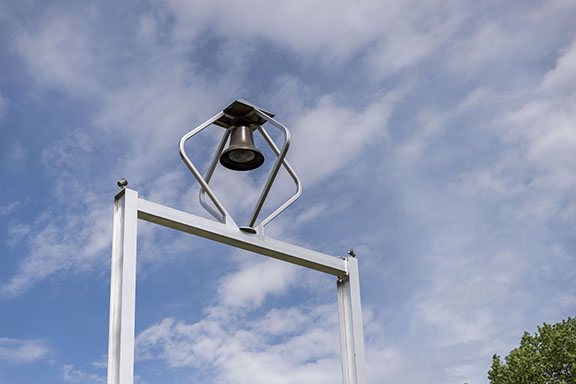 The top of the PNW bell tower pictured in front of a blue, cloudy sky