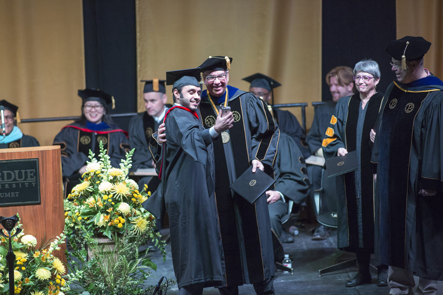 Chancellor Keon taking a selfie with a graduating student on stage