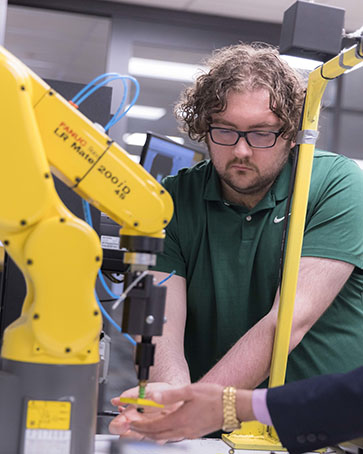 A PNW student works with a robot