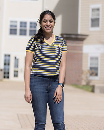 A student stands outdoors and smiles at the camera