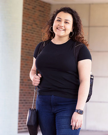 A PNW student stands outside a building