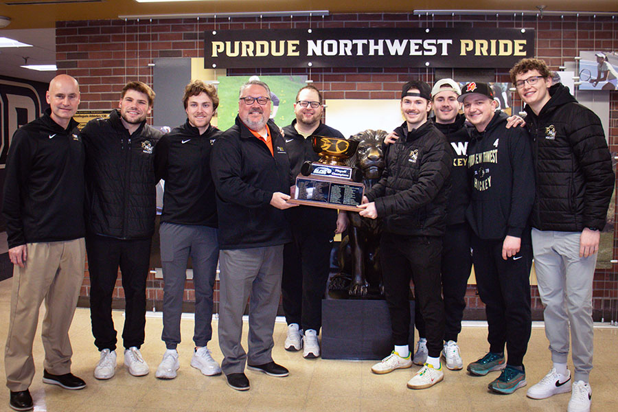 Hockey team members and Purdue Northwest coaches and administrators pose with a trophy.