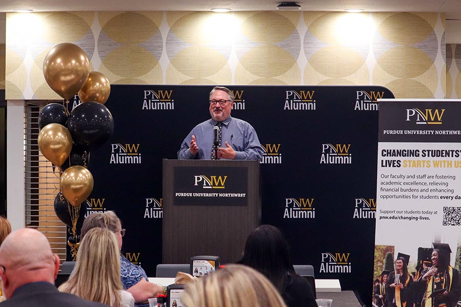 PNW Chancellor Kenneth C. Holford speaks in front on a PNW Alumni banner
