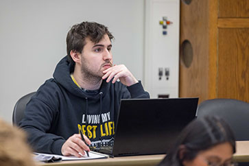 A student in a PNW Housing sweatshirt sits in class.