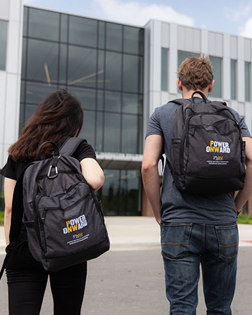 Two students wear "Power Onward" backpacks and walk toward the Nils K. Nelson Bioscience and Innovation Building