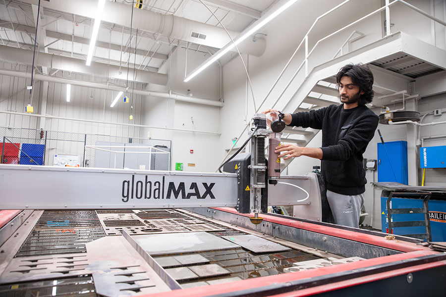 A student uses a large water jet cutting machine.