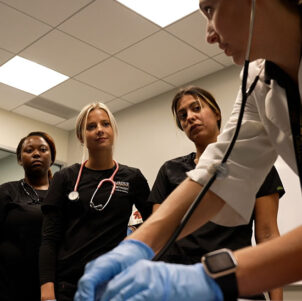 Three nursing students look at their instructor