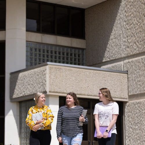 Three students walk together outside.