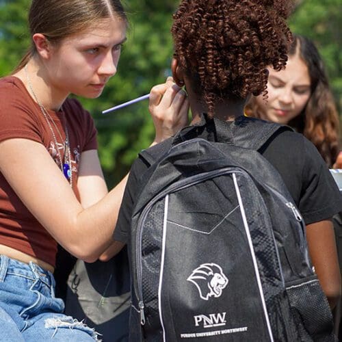 A girl gets her face painted at PNW's backpack giveaway.