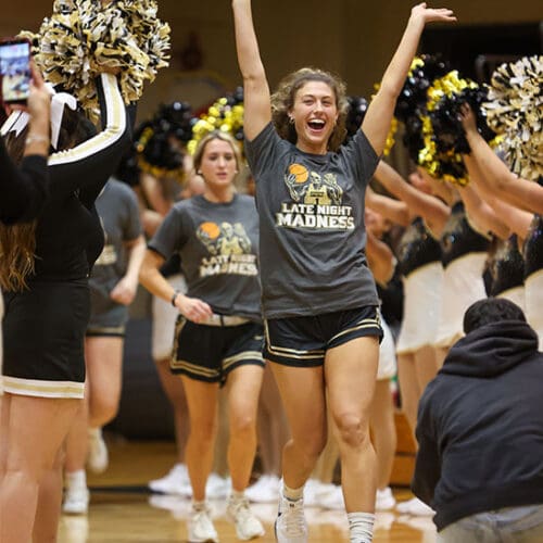 PNW women's basketball players walk between rows of cheerleaders and dance team members.