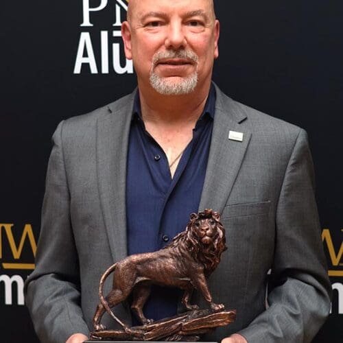 A man in a suit holds a lion sculpture on a base.