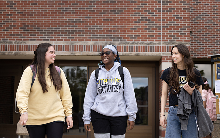 Three students walk together outside of the Classroom Office Building