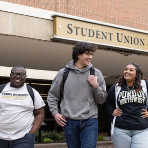 Three students walk together outside of the Student Union Library Building.
